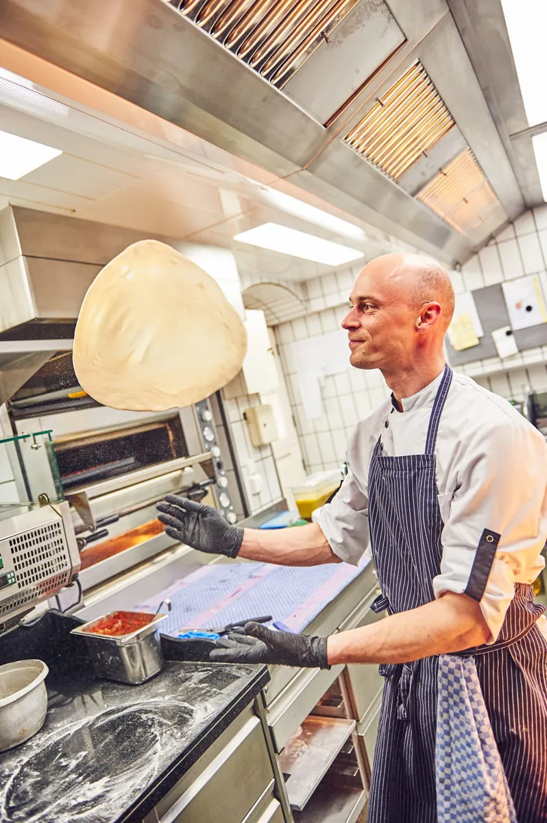Pizzabäcker am Ofen im Ristorante Engel, Teig in der Luft